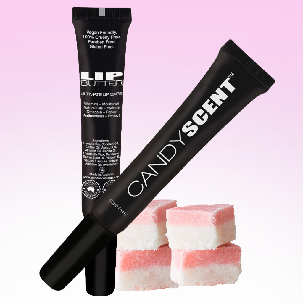 Two black squeeze tubes of lip products, branded "Lip Butter" by CANDYSCENT™, are displayed against a pink gradient background. Below the tubes, there are four pink and white layered square candies. Featuring natural ingredients, both tubes have white text detailing their moisturizing properties.