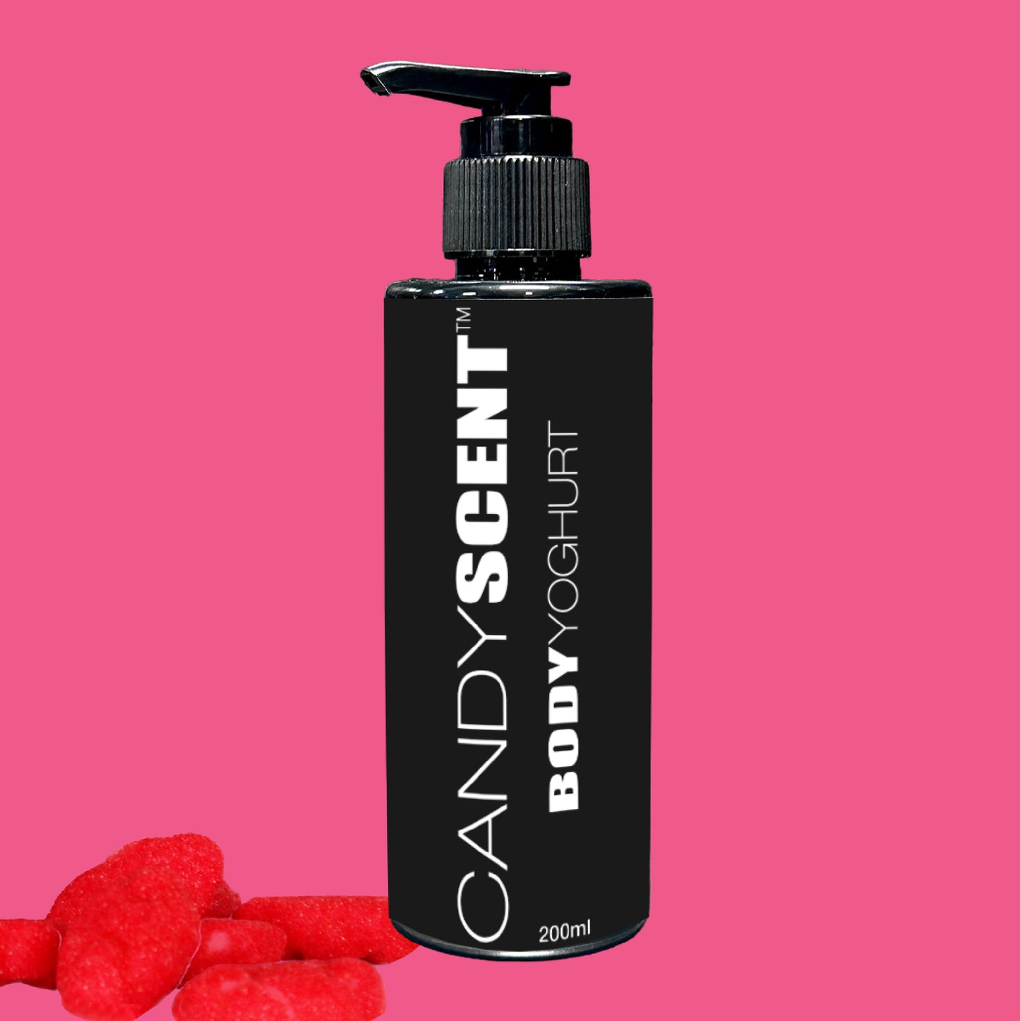 A black bottle featuring the "Body Yoghurt" by CANDYSCENT™ with a pump dispenser is set against a pink backdrop, offering promises of nourishment. In the foreground, red heart-shaped gummies contribute to a sweet atmosphere.