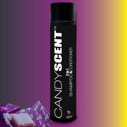 A 300ml bottle of CANDYSCENT™ 2 in 1 Shampoo & Conditioner with a black label is centered against a purple to yellow gradient background. In the bottom left corner of the image, partially visible pink wrapped soap bars promise a silky finish for your hair.