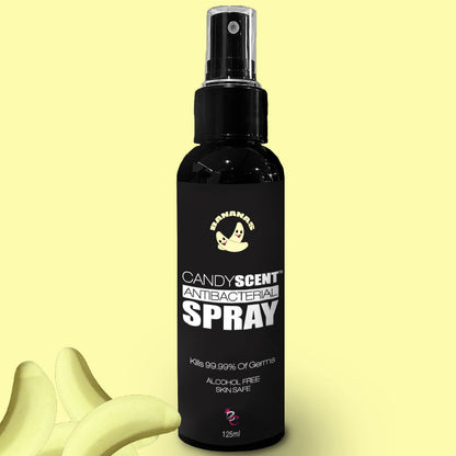 Image of a black bottle labeled "CANDYSCENT™ Antibacterial Spray" with a volume of 125ml. The label claims it kills 99.99% of germs and is alcohol-free and skin-safe. The background features yellow banana graphics with a banana emoji on the bottle's label.