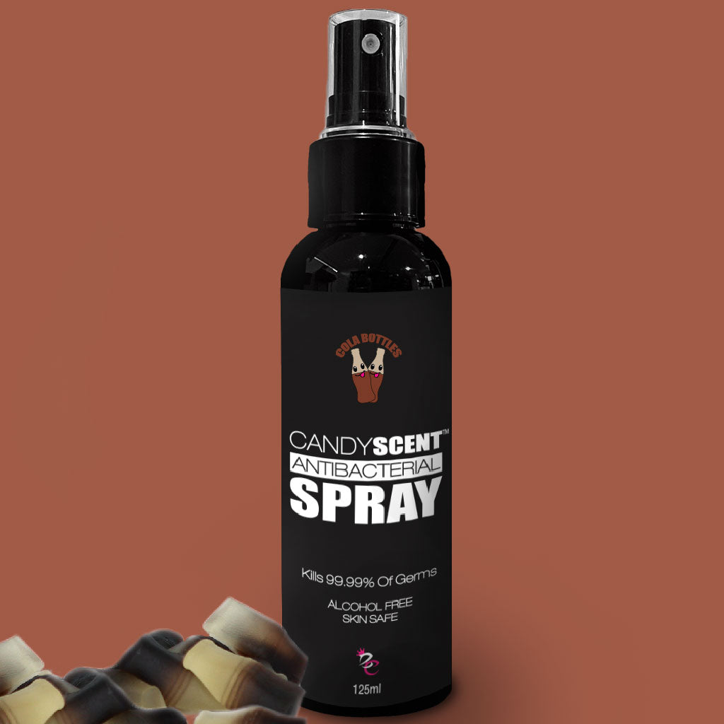 A black 125ml spray bottle labeled "Antibacterial Spray" by CANDYSCENT™ features a bear logo at the top and includes descriptions such as "Kills 99.99% of Germs," "Alcohol-Free," and "Skin Safe." Set against a brown background, it also has a bear-themed cap in the corner.