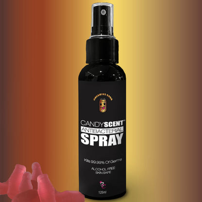 A spray bottle labeled "CANDYSCENT™ Antibacterial Spray," boasting that it kills 99.99% of germs, is alcohol-free, and skin-safe. The bottle is black with a red and yellow gradient background, featuring red gummy bear shapes in the lower left.