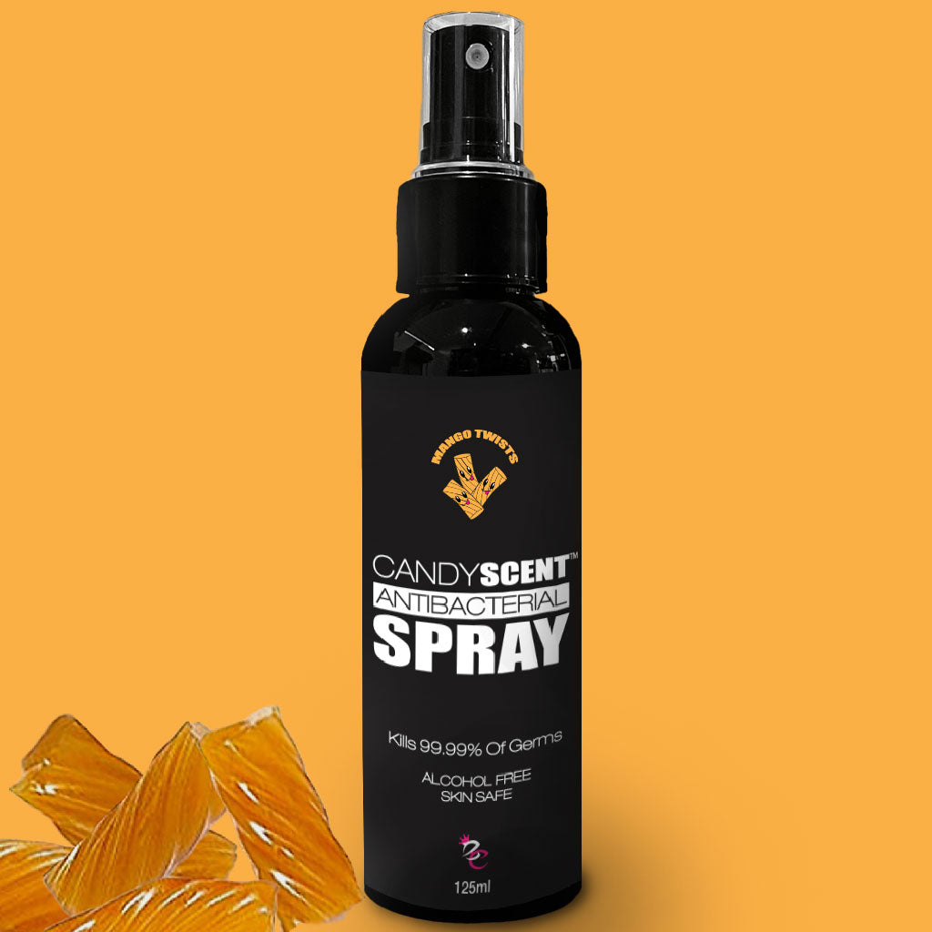 A black spray bottle labeled "Antibacterial Spray" by CANDYSCENT™ on an orange background. The alcohol-free and skin-safe bottle, which claims to kill 99.99% of germs, holds 125ml of product. It is framed by orange candy slices at its base, emphasizing its sweet appeal.