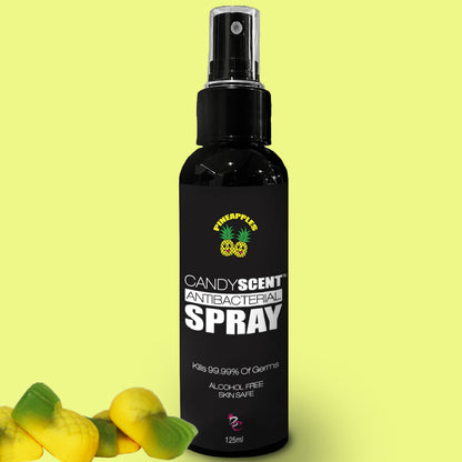 A black bottle labeled "CANDYSCENT™ ANTIBACTERIAL SPRAY" from the brand Pineapple, set against a lime green background. This alcohol-free, skin-safe spray promises to kill 99.99% of germs and comes in a 125ml bottle. Candy-shaped items are positioned at the bottom left of the scene.