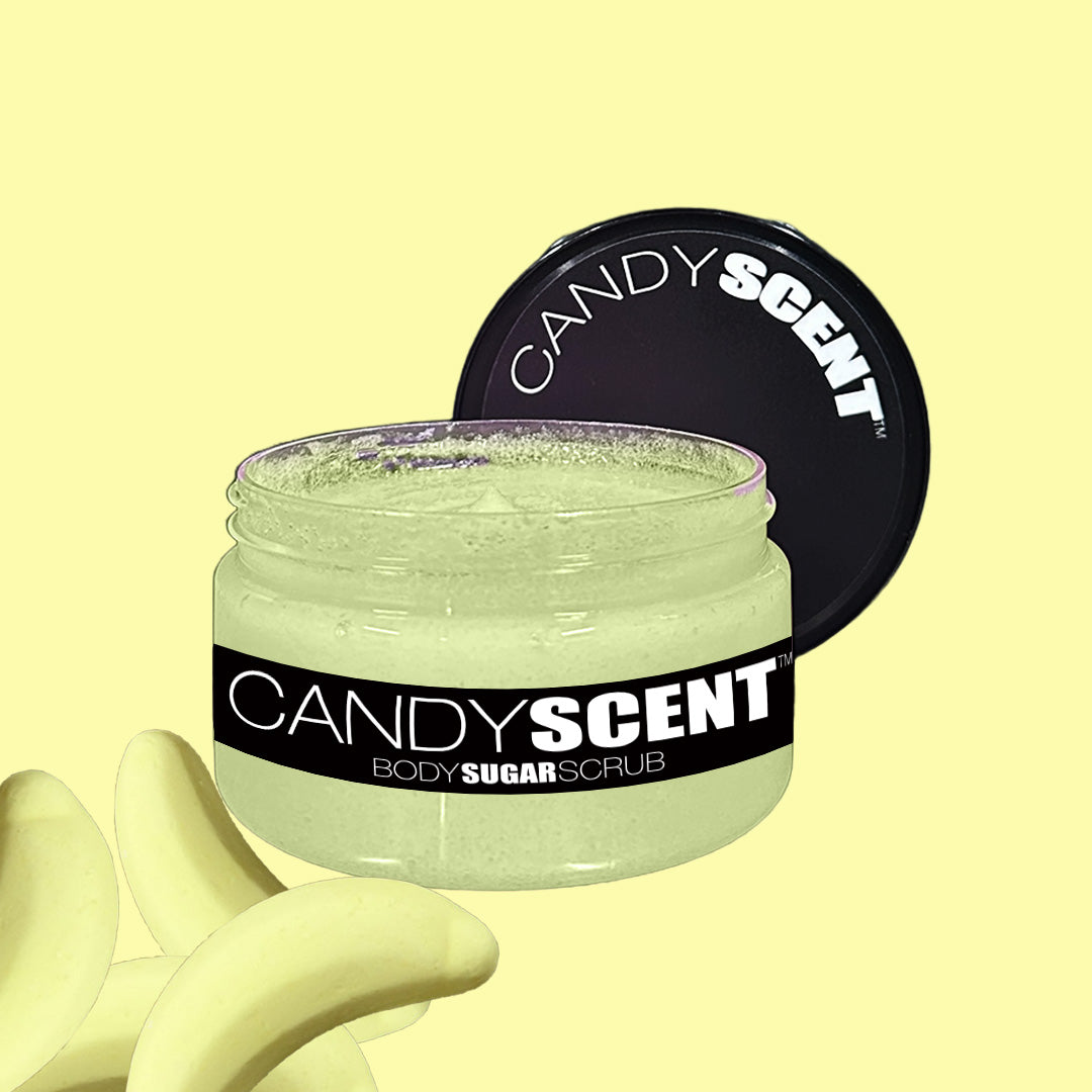 A jar of CANDYSCENT™ Body Sugar Scrub is opened, revealing a pale yellow, sugar-like scrub inside. The black product label with white text stands out. Formulated with nourishing oils to exfoliate and hydrate, the scrub sits next to banana-shaped candy pieces against a solid light yellow background.