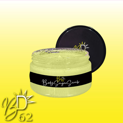 A clear glass jar of yellow Body Sugar Scrub with a black lid sits proudly behind it. The jar features a black label with "BD62" and "Body Sugar Scrub" in white cursive. Perfect for all skin types, this scrub from BOOTY DUPE promises to exfoliate and hydrate. The background fades from yellow to white, showcasing the "BD62" logo in the bottom left corner.