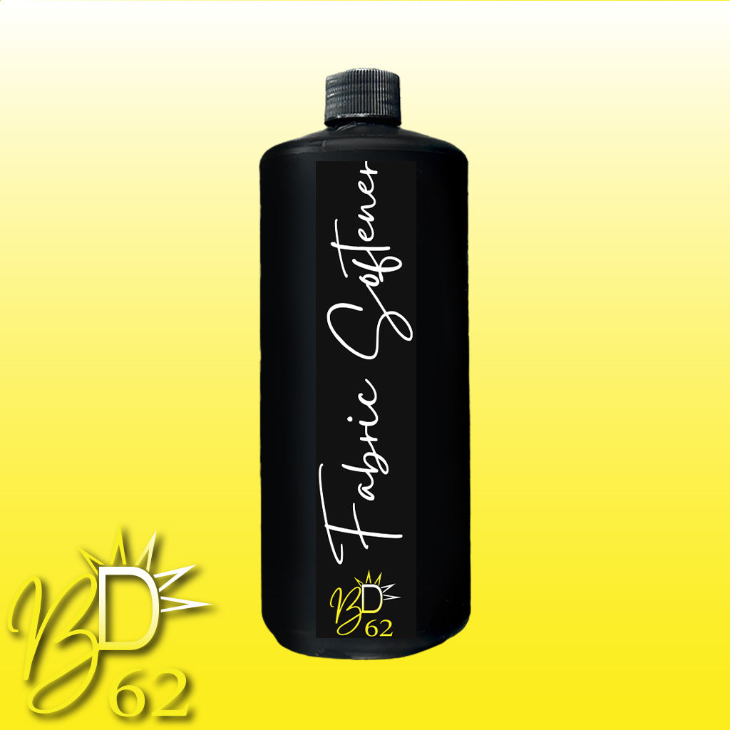 A black bottle, complete with a matching black cap, is labeled "BOOTY DUPE Fabric Softener" in elegant white cursive text. The bottom of the bottle showcases a stylized "BD 62" logo. The backdrop transitions from yellow at the bottom to white at the top, featuring the "BD 62" logo in the lower-left corner.