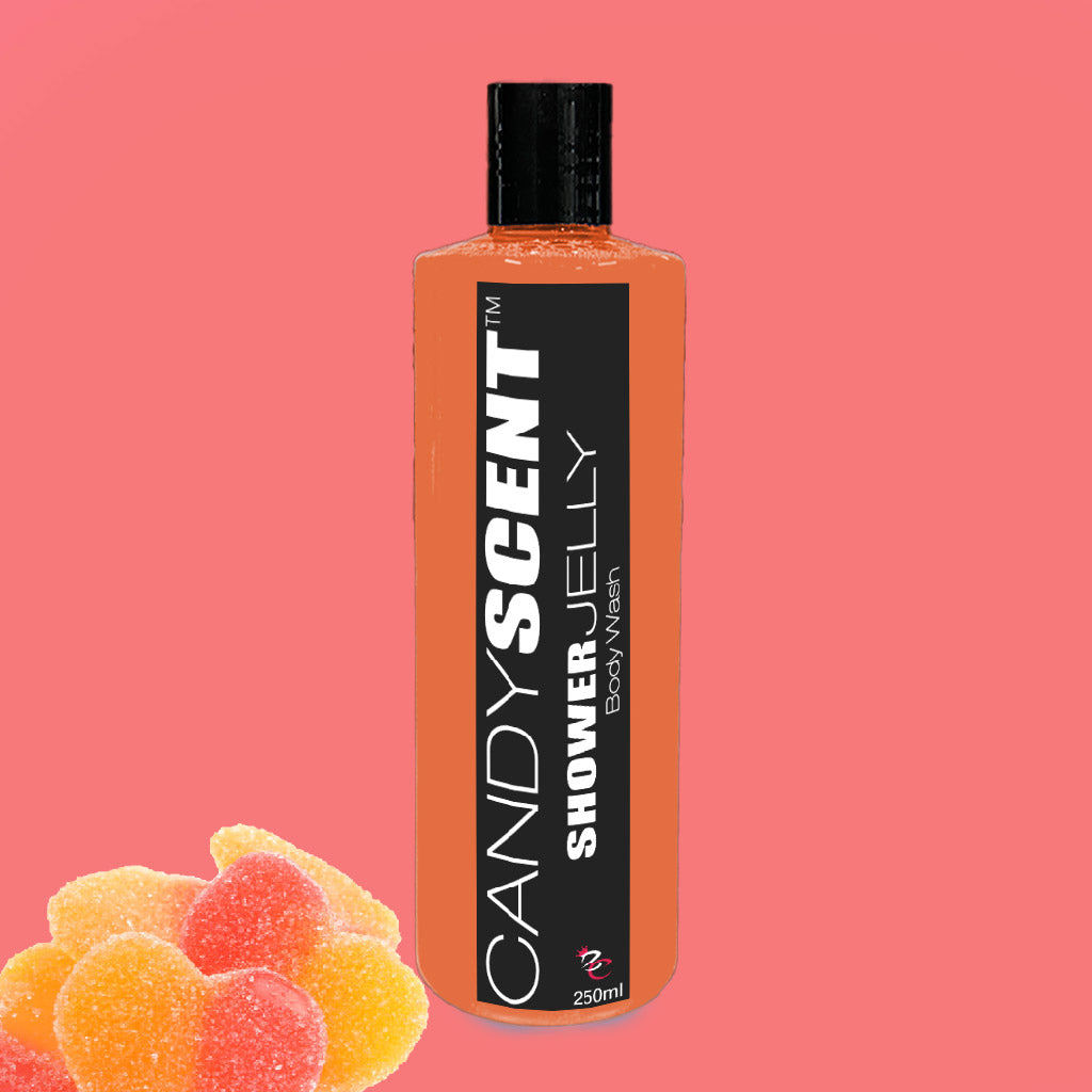 A bottle of CANDYSCENT™ Shower Jelly Body Wash with a black cap, set against a pink background. The cylindrical bottle has an orange label with the product name in black and white text. On the bottom left of the image are three gummy heart-shaped candies.