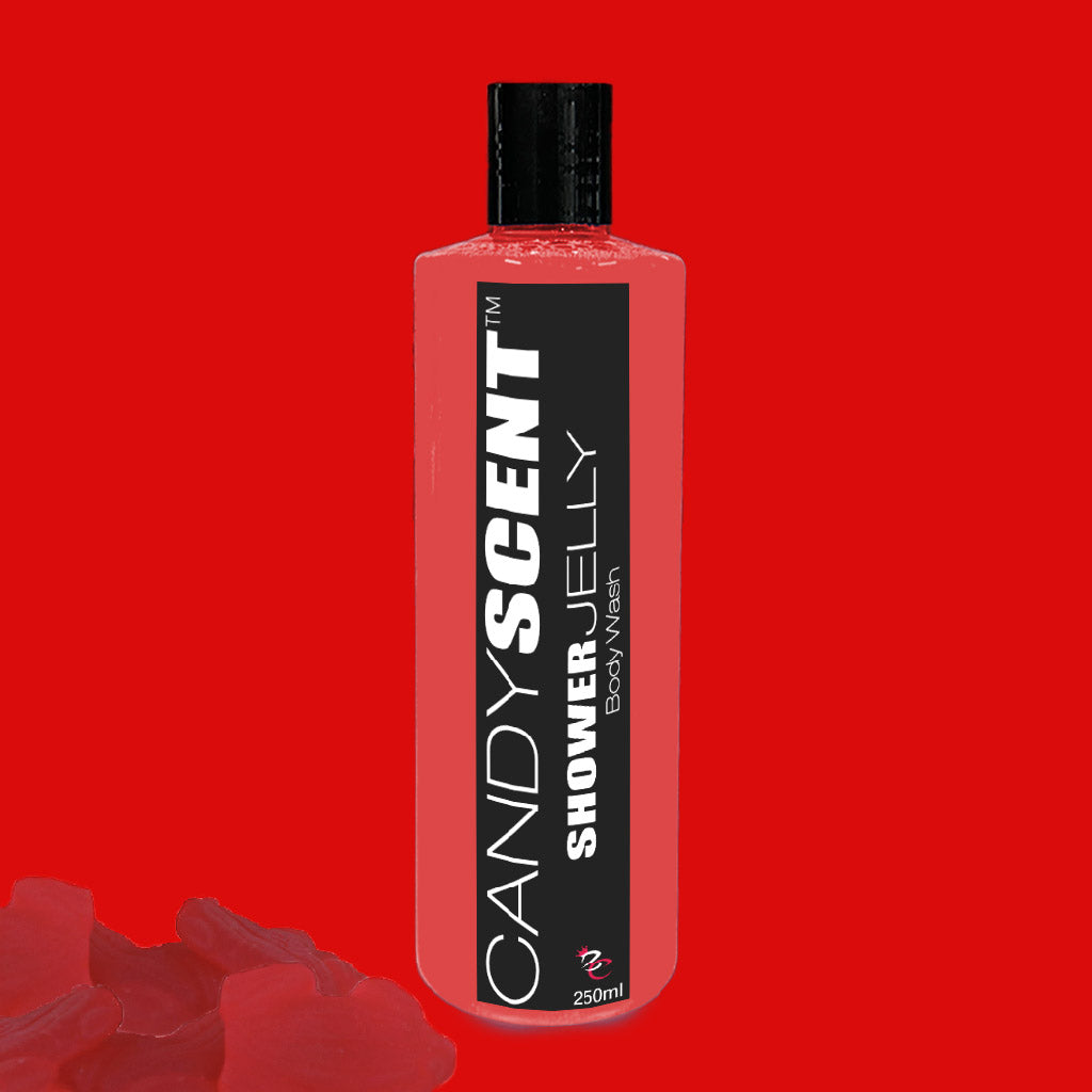 A bright red bottle of Shower Jelly Body Wash from CANDYSCENT™ against a solid red background. The bottle features a black cap and a black label with white text. In the lower left corner of the image, small red jelly-like pieces are scattered.