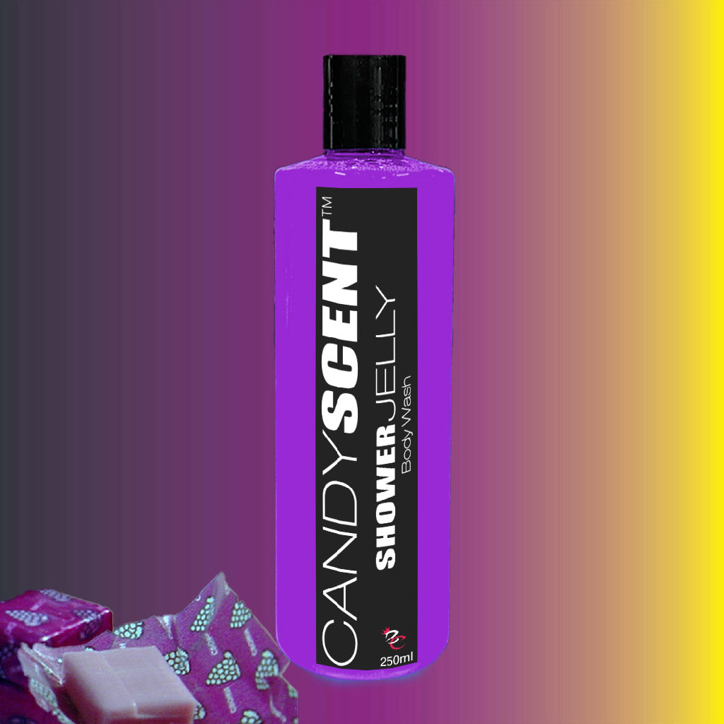 Image of a vibrant purple bottle of "Shower Jelly Body Wash" by CANDYSCENT™, standing against a gradient background that fades from red to yellow. The bottle, recognized for its moisturizing properties, features a black cap. To the left, there are soap bars in colorful packaging.