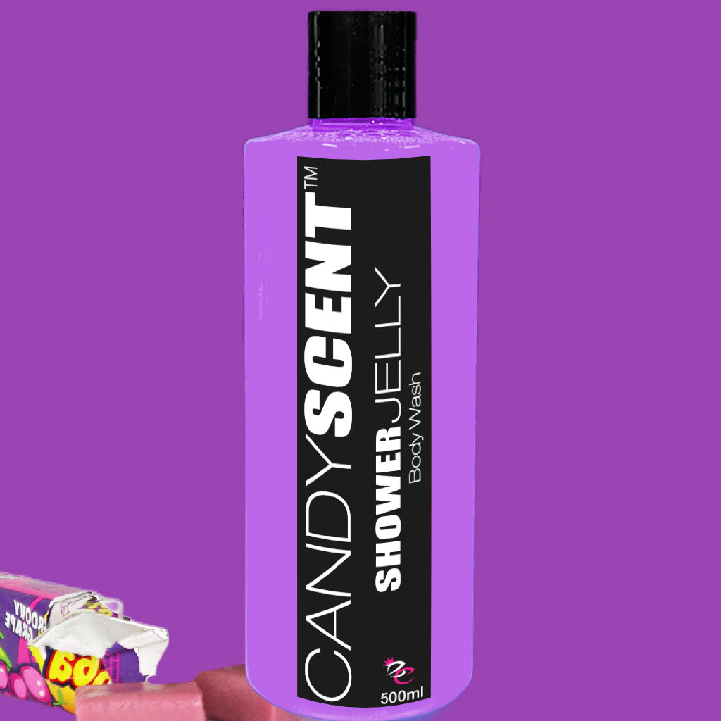 A bottle of CANDYSCENT™ Shower Jelly Body Wash is shown against a purple background. The bottle is purple with a black label and white text detailing the product name and volume, 500ml. A partially visible pink candy wrapper is at the bottom left corner.