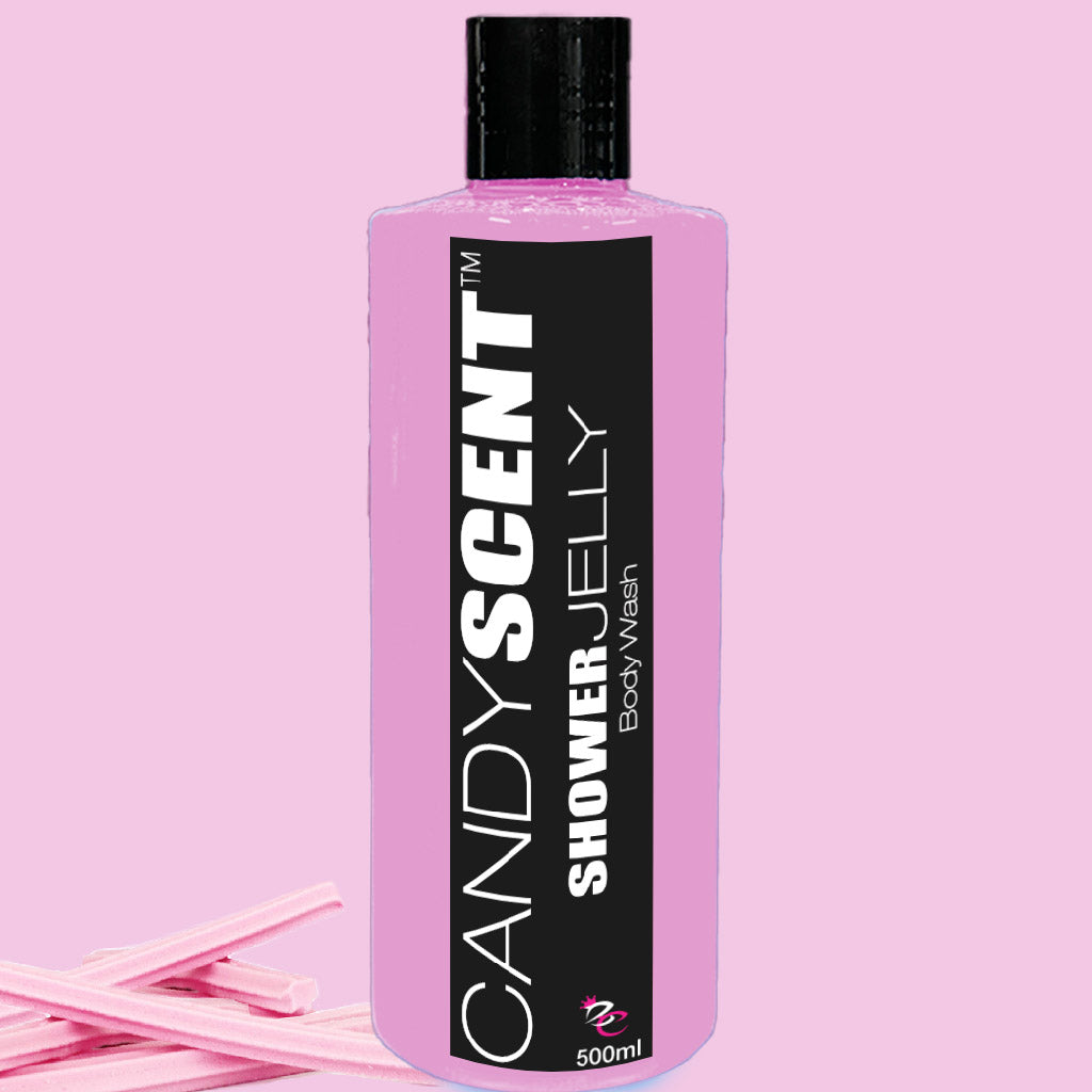 A 500ml pink bottle of CANDYSCENT™ Shower Jelly Body Wash with a black label stands against a matching pink background. To the left of the bottle are a few pink candy sticks.