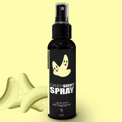 An image of a 125ml bottle of CANDYSCENT™ Car & Home Scent Spray air freshener, featuring a black bottle with a yellow banana design and spray nozzle. Three candy bananas are displayed next to the bottle on a pale yellow background, promoting a long-lasting fragrance that eliminates odors.