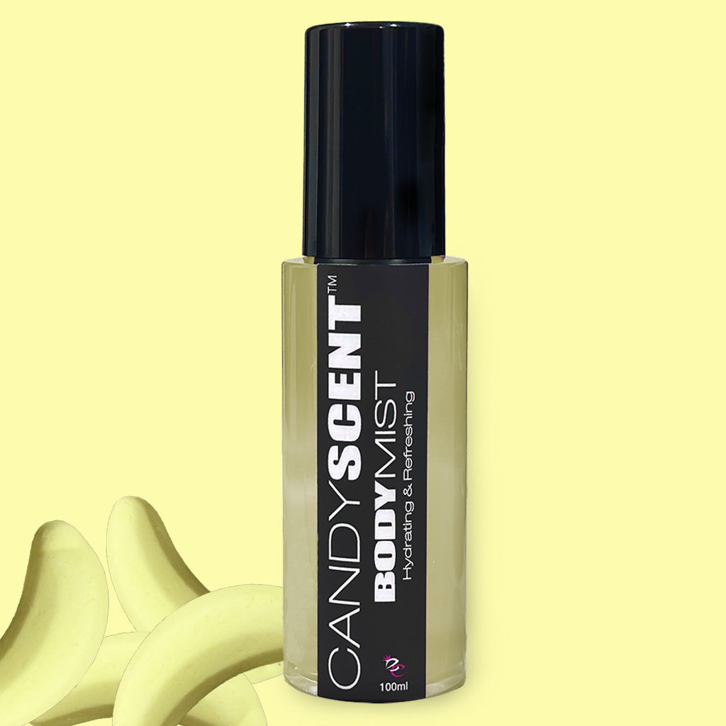 A black and transparent spray bottle labeled "CANDYSCENT™ Hydrating Body Mist, 100ml" stands against a yellow background with banana-shaped candies in the bottom left corner. Infused with Witch Hazel for extra hydration and refreshment.