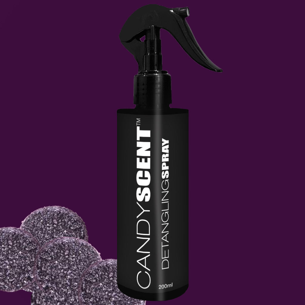 A 200ml black bottle of CANDYSCENT™ Hair Detangling Spray with a spray nozzle is set against a dark purple background. The bottle, suitable for all hair types, boasts white text and is infused with Aloe Vera. Purple, textured spheres can be seen in the bottom left corner of the image.