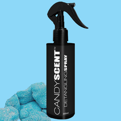 A bottle of CANDYSCENT™ Hair Detangling Spray, featuring a black spray nozzle, is displayed against a light blue backdrop. The sleek black bottle, embellished with white lettering, contains 200ml of this detangling wonder enriched with Jojoba Oil and Aloe Vera. Blue candy-like objects in the bottom left corner add a whimsical element to the scene.