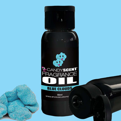 Image of a 50ml bottle labeled "Fragrance Oil" by CANDYSCENT™, with the fragrance name "BLUE CLOUDS" displayed underneath. The label features a logo of two smiling blue clouds, set against a light blue background with a pile of sugar-coated blue candy-like objects beside it—ideal for freshening your home scent using an oil burner.