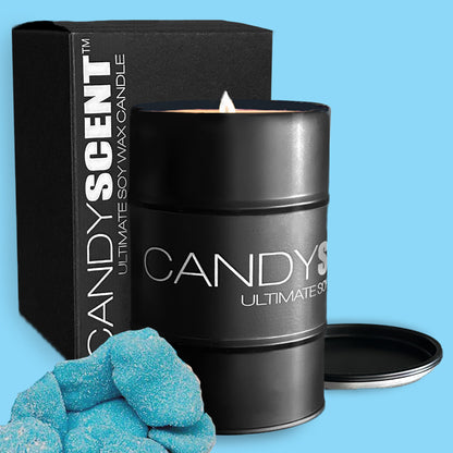 A lit black cylindrical candle with the text "CANDYSCENT™ Soy Wax Candle Tin" on the label is shown against a blue background. Behind it is the black packaging box with the same text. Beside the candle, there are blue sugar-coated gummies, emphasizing its delightful scent.