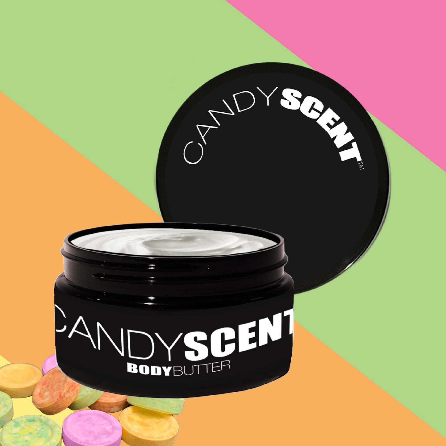 An open black jar of CANDYSCENT™ Body Butter, rich with a Candy Scent, reveals its creamy white nourishment. The backdrop features diagonal pastel stripes in green, pink, and orange and is complemented by a vibrant array of colorful candies in the corner.