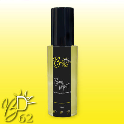 A bottle of Hydrating Body Mist from the brand Booty Dupe. The bottle has a glossy black cap and is labeled "Body Mist" with "Hydrating & Refreshing" written underneath. The background is a gradient of yellow, and the Booty Dupe logo is displayed at the bottom left corner.