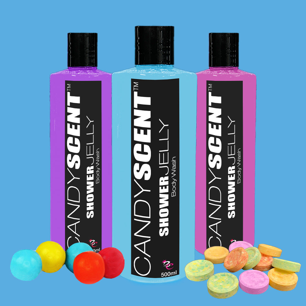 Three bottles of CANDYSCENT™ Shower Jelly Body Wash are displayed against a blue background. The purple, blue, and pink 500ml bottles, each with black caps, promise a luxurious shower experience. Colorful candies are scattered at the base of the vibrant bottles.