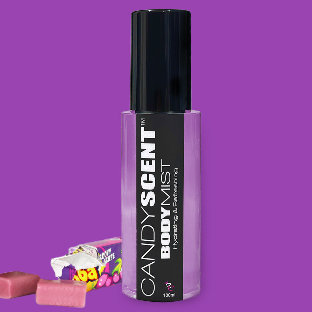 A purple-themed image featuring a 100ml bottle of CANDYSCENT™ Hydrating Body Mist with a black cap and label. The label reads "CANDYSCENT™ BODY MIST Hydrating & Refreshing". Next to the bottle are pieces of pink candy and candy packaging, showcasing its nourishing ingredients for a refreshing feel.