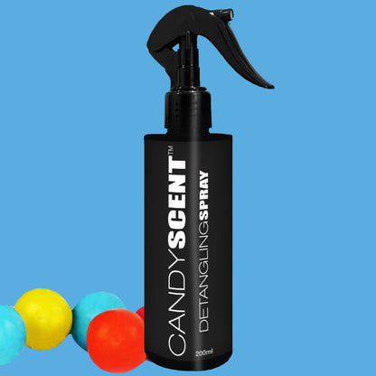 A black 200ml spray bottle labeled "CANDYSCENT™ Hair Detangling Spray" with Aloe Vera is set against a blue background. The bottle features a black nozzle. Adding a playful touch, three colorful balls in yellow, blue, and red are positioned near the bottom left corner of the image.