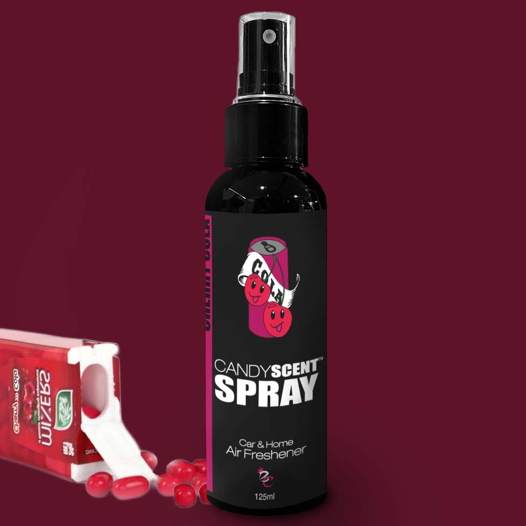 A black spray bottle labeled "CANDYSCENT™ Car & Home Scent Sprays" adorned with cherry graphics stands upright against a dark red background. Promising to eliminate odors with a long-lasting fragrance, it is positioned next to a partially open pack of cherry-flavored Tic Tac mints, allowing a few red mints to spill out nearby.