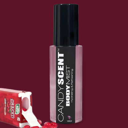 A bottle of CANDYSCENT™ Hydrating Body Mist with nourishing ingredients, featuring a black cap and label, sits next to a partially opened pack of green apple-flavored Wrigley's Extra gum with some pieces visible, all set against a maroon background.