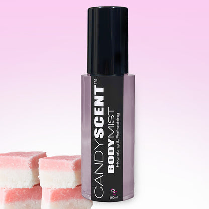 A black and white bottle of CANDYSCENT™ Hydrating Body Mist, labeled as "Hydrating & Refreshing," is displayed against a pink gradient background. Infused with witch hazel, the bottle has a black cap, and three pink and white square layered candies are situated at the bottom left corner.