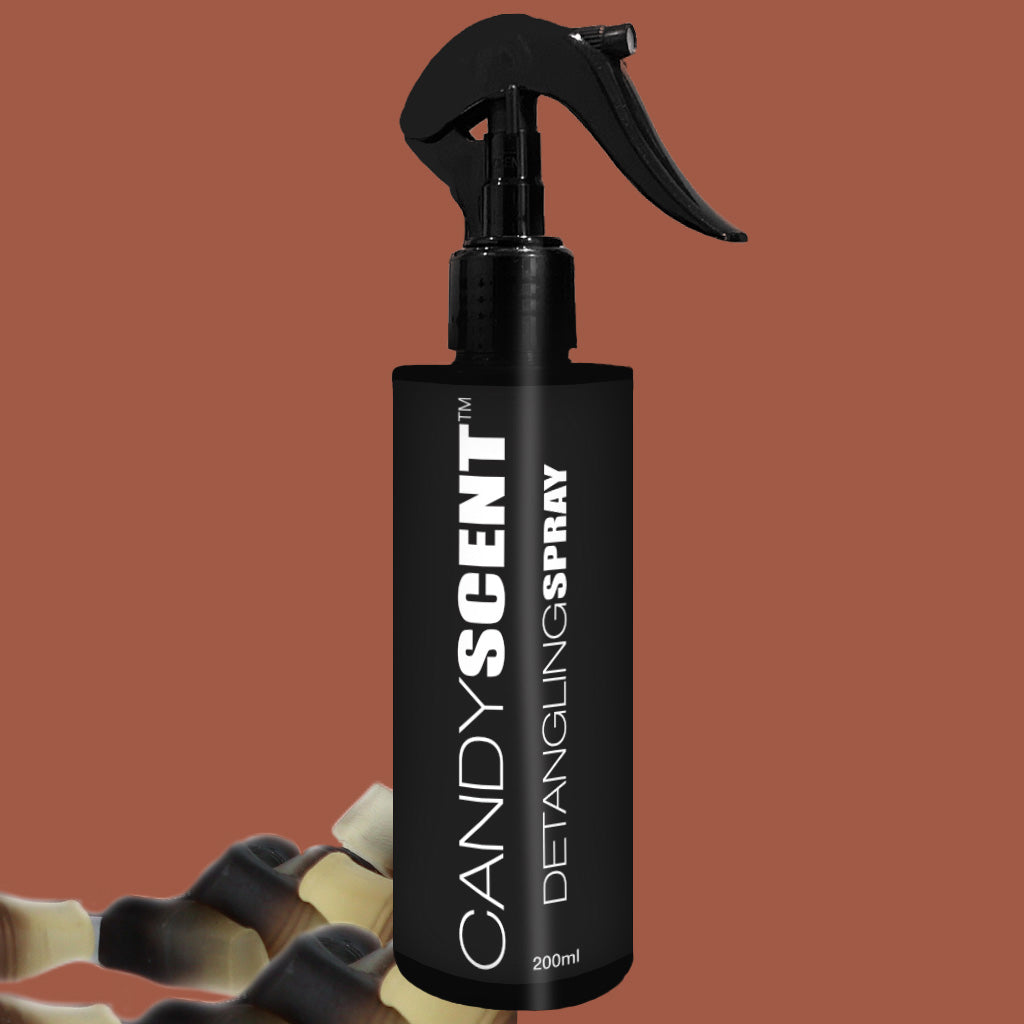 A black spray bottle labeled "CANDYSCENT™ Hair Detangling Spray" with a volume of 200ml is set against a brown background. A few black and white hair curlers are partially visible at the bottom, highlighting the nourishing blend of aloe vera and jojoba oil in every spritz.