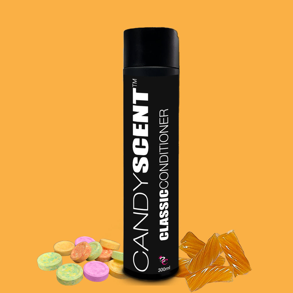 A black bottle labeled "Classic Conditioner" by CANDYSCENT™ is set against an orange background. The 300ml bottle features a black cap and is surrounded by colorful candy discs and wrapped amber-colored candies. Infused with macadamia oil, this conditioner promises a sweet and nourishing experience.