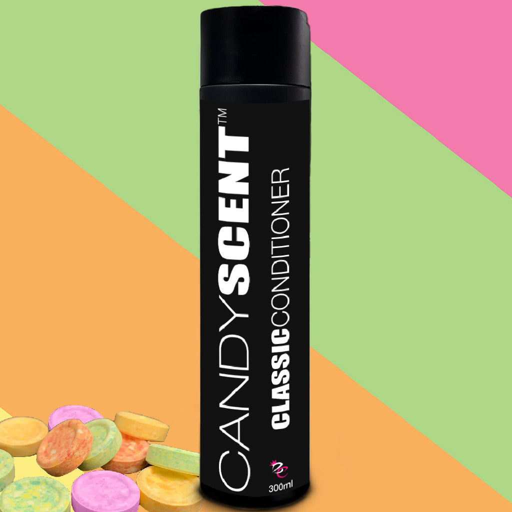 A bottle from the Classic Shampoo & Conditioner Bundle by CANDYSCENT™ is displayed against a backdrop with diagonal stripes in pink, green, and orange. The bottle is black with the brand name in white text. Several colorful, round candies are placed at the bottom left corner of the image.