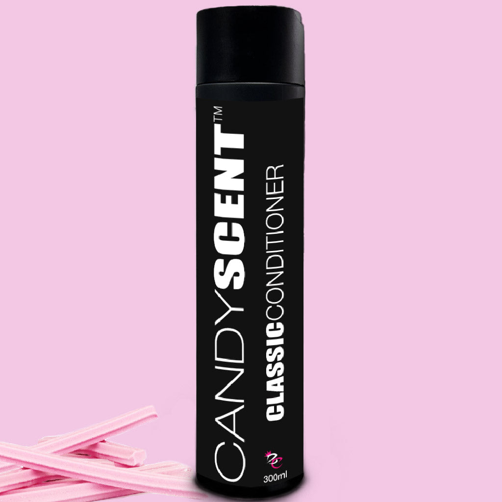 A black cylindrical bottle labeled "CANDYSCENT™ Classic Shampoo & Conditioner Bundle" in white text sits against a pink background. The 300 ml bottle is accompanied by several pink candy sticks placed to its left.