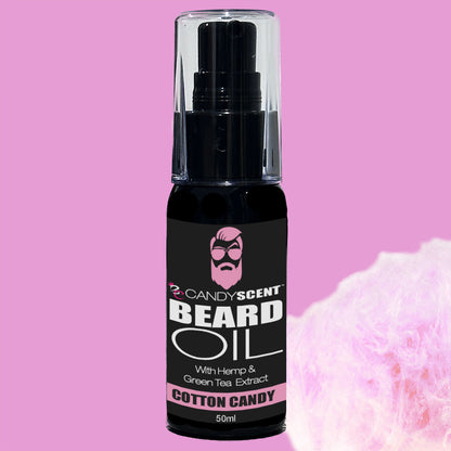 Introducing CANDYSCENT™ Beard Oil, adorned with a pink label featuring a bearded cartoon face. Infused with hemp and green tea extract and boasting a delightful Cotton Candy scent, this 50ml bottle promotes optimal beard health. Set against a pink background with cotton candy, it’s an essential addition to your grooming routine.