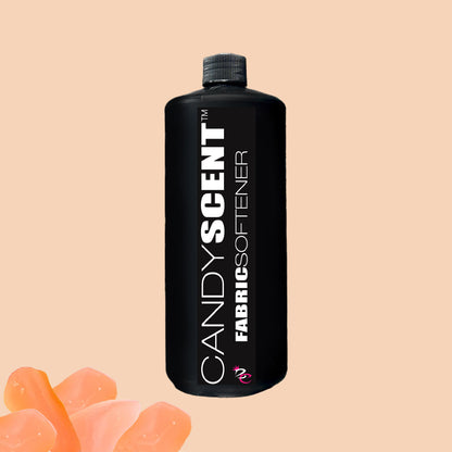 A black bottle labeled "Fabric Softener" from CANDYSCENT™ with a black cap, set against a beige background. Orange rose petals are scattered in the lower left corner, emphasizing the softener's promise of static-free freshness.