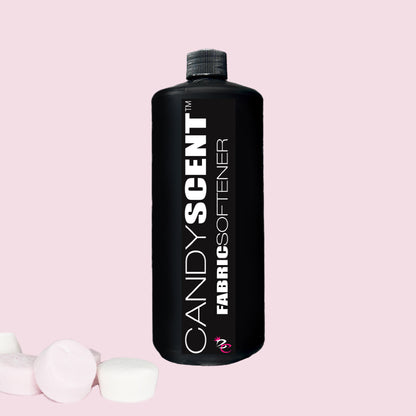 A black bottle labeled "Fabric Softener" from CANDYSCENT™ is set against a pink background, offering wrinkle-free freshness. Three marshmallows are positioned beside the bottle.