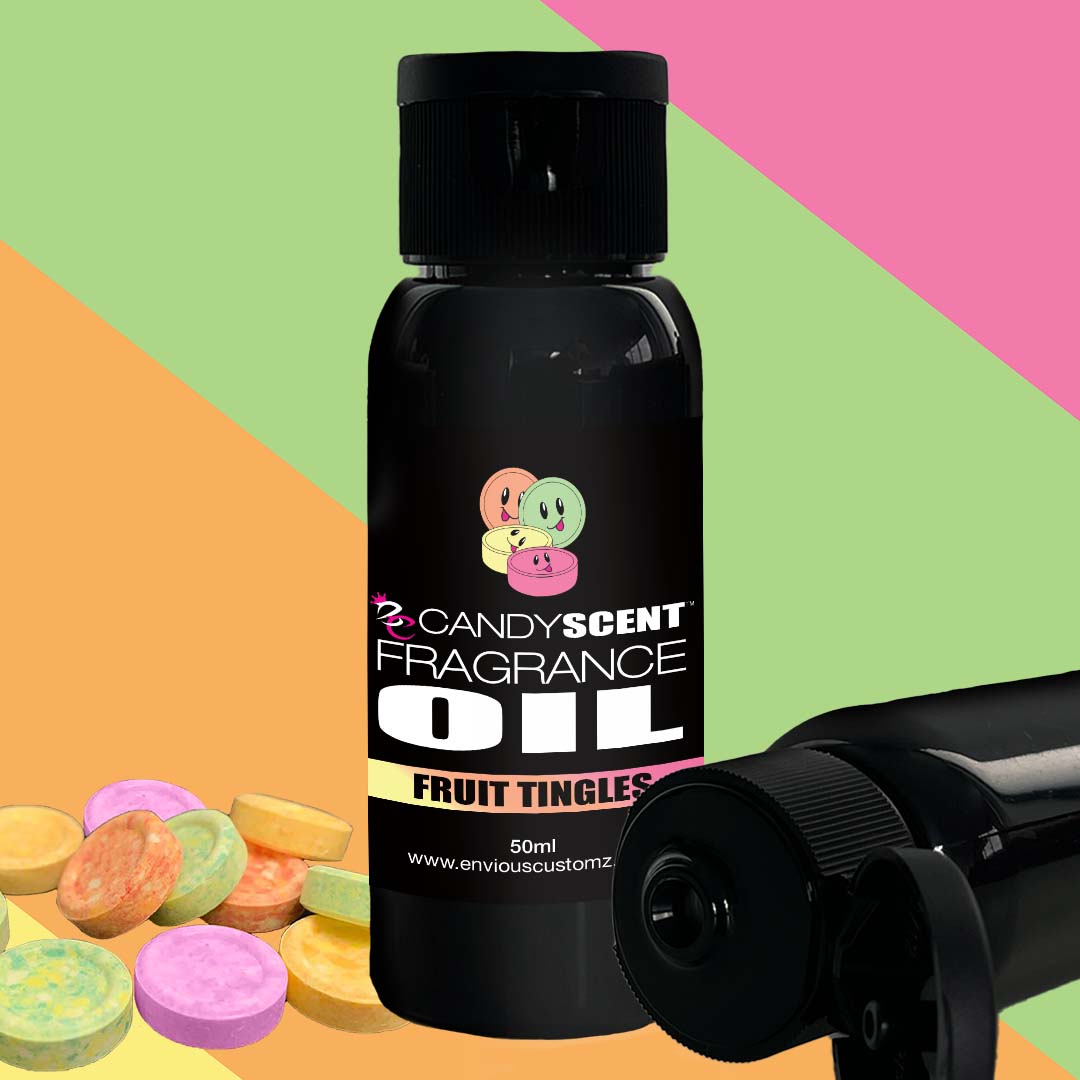 A black bottle labeled "CANDYSCENT™ Fragrance Oil" stands against a colorful background with pink, green, and yellow sections. Next to the bottle are assorted round candies and an open bottle laying on its side—perfect for your favorite oil burner or to enhance your home scent.