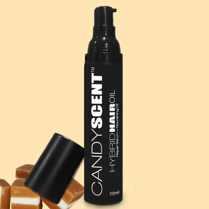 A 50ml bottle of CANDYSCENT™ Hybrid Hair Oil, branded "Repair Serum + Nourishing Hair Oil," is positioned against a light yellow backdrop. The bottle's pump dispenser sits beside its cap, complemented by pieces of caramel.