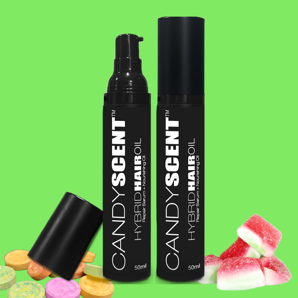 Two black bottles of CANDYSCENT™ Hybrid Hair Oil are displayed on a bright green background, surrounded by colorful candy pieces. One bottle has its cap off, revealing a pump dispenser, while the other remains fully capped. This nourishing hair oil doubles as a repair serum to rejuvenate and protect your locks.