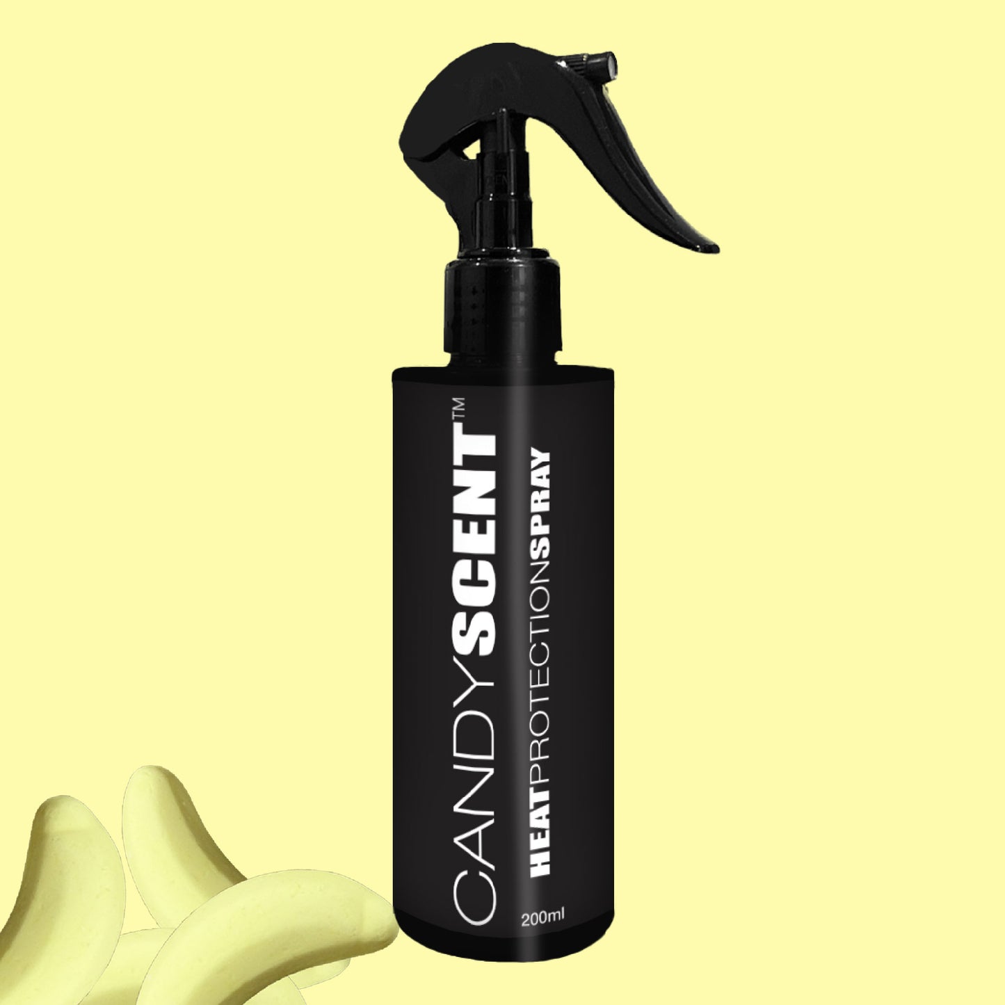 A black CANDYSCENT™ Heat Protection Spray bottle with a trigger nozzle is set against a light yellow background, offering salon-quality results complemented by the whimsical presence of banana-shaped yellow objects in the bottom left corner.