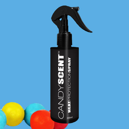 A black bottle of CANDYSCENT™ Heat Protection Spray stands against a light blue background, with vibrant red, yellow, and blue balls adding a playful touch in the bottom left corner.