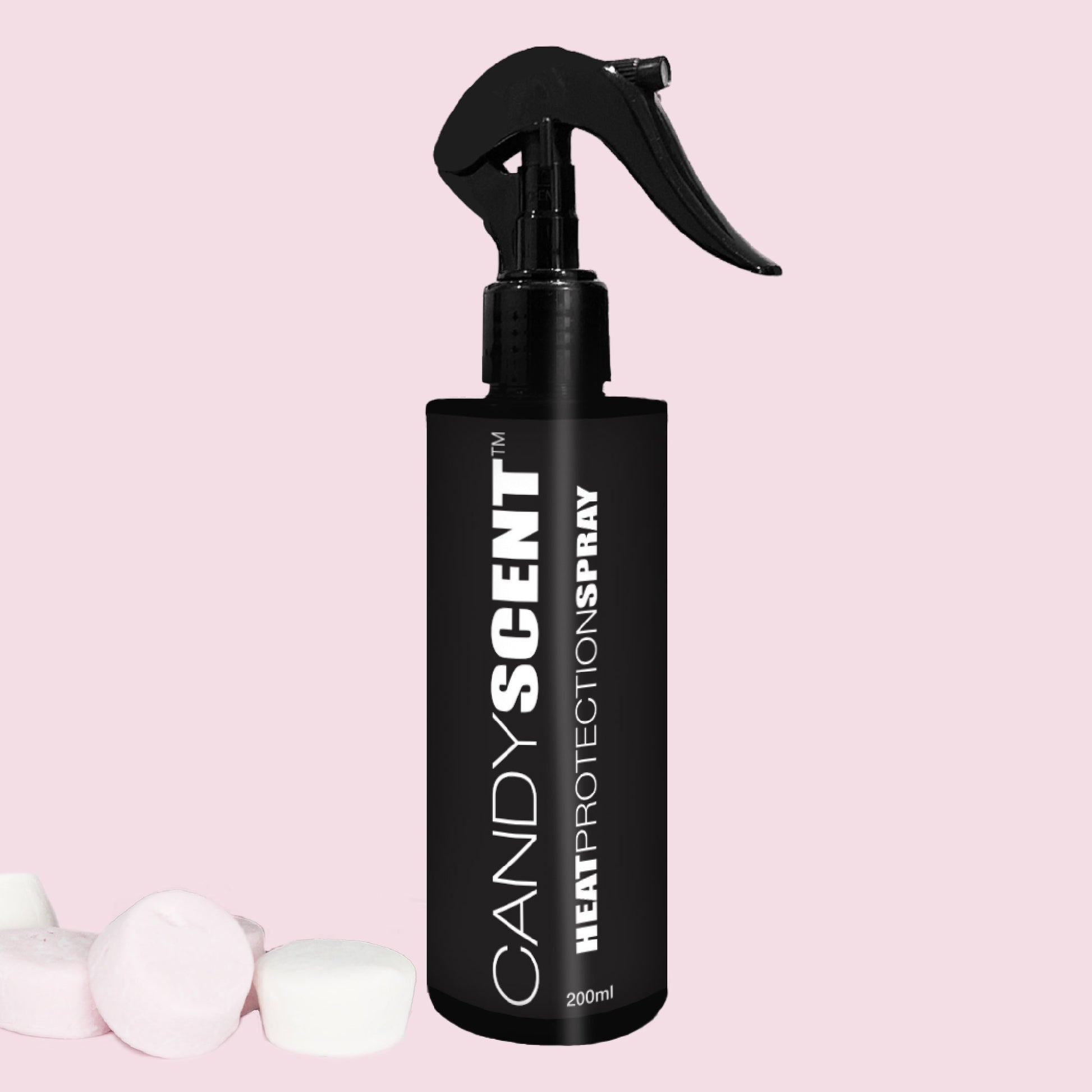 A black spray bottle featuring the label "Heat Protection Spray" from CANDYSCENT™ offers salon-quality results against a pink backdrop. Equipped with a trigger nozzle for easy application, the product is complemented by three marshmallows that suggest its sweet fragrance, making it ideal for strengthening hair and providing heat protection.