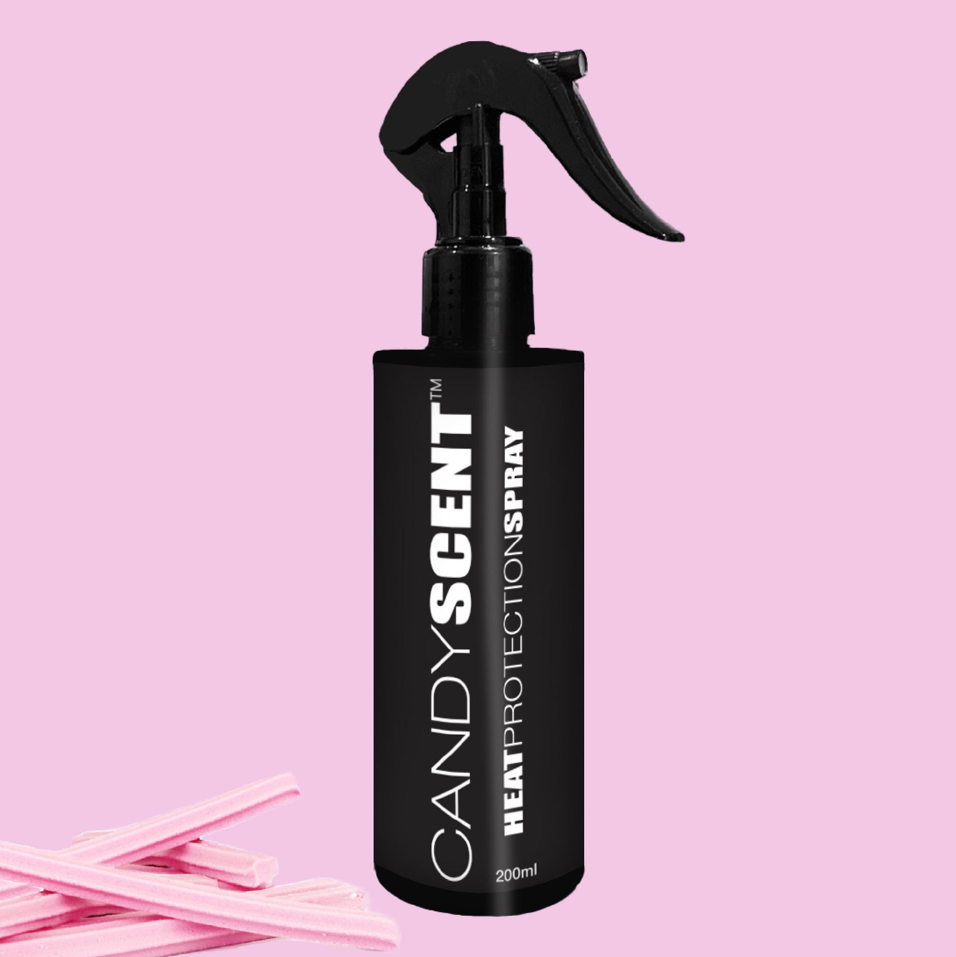 A black bottle of CANDYSCENT™ Heat Protection Spray set against a pink backdrop showcases its pump-style nozzle for salon-quality results. Pink candy sticks beside the bottle enhance its sweet appeal while ensuring optimum hair strengthening.