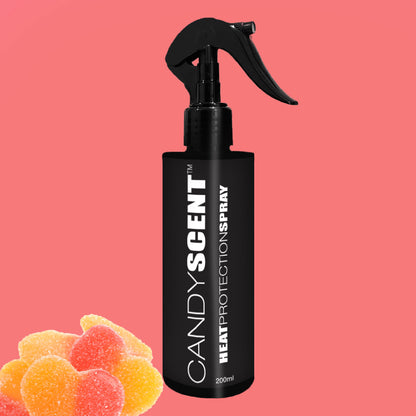 A black bottle labeled "CANDYSCENT™ Heat Protection Spray" promises salon-quality results and is beautifully showcased against a pink background. Equipped with a spray nozzle, it's surrounded by vibrant gummy candies in the bottom left corner, evoking a sense of playful charm.