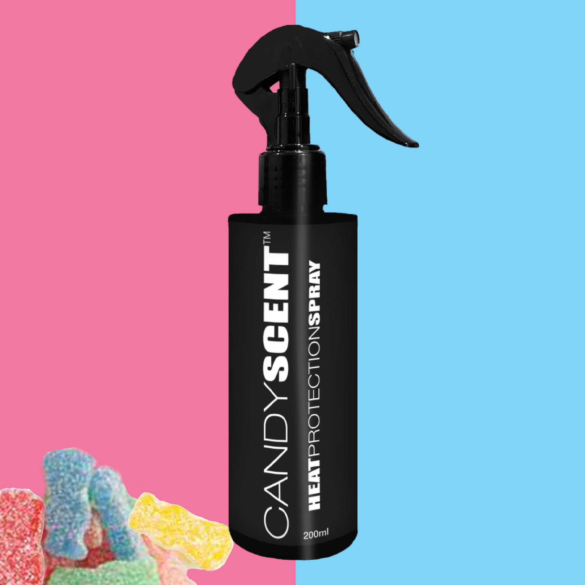 A black bottle of CANDYSCENT™ Heat Protection Spray with a spray nozzle stands against a split pink and blue backdrop. Infused with the signature CANDYSCENT™, it promises salon-quality results. In the bottom left corner, colorful gummy candies add a playful touch.