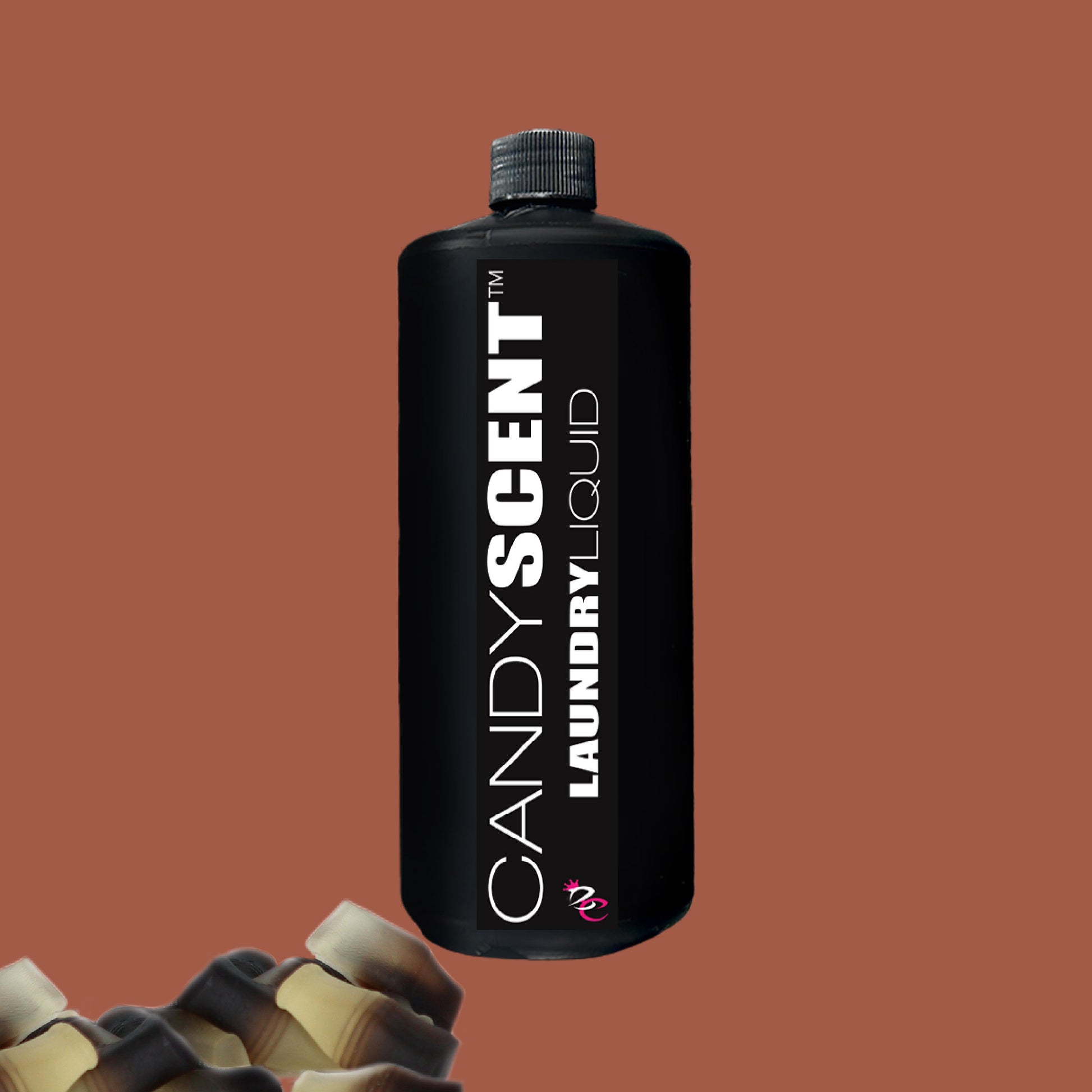 A black bottle labeled "CANDYSCENT™ Laundry Liquid" stands upright against a brown background, highlighting its eco-friendly, biodegradable formula. A portion of another bottle is visible at the bottom left corner.