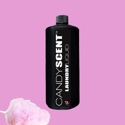 A black bottle labeled "Laundry Liquid" from CANDYSCENT™ is set against a pink background, nestled in fluffy pink cotton candy. This eco-friendly formula ensures biodegradable ingredients and imparts a delightful fragrance to your clothes.