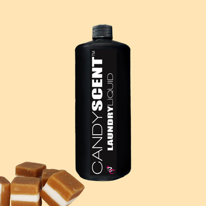 A black bottle labeled "Laundry Liquid" from CANDYSCENT™ stands against a beige background, exuding an eco-friendly vibe. In the bottom left corner, several caramel-colored candies with white stripes add a touch of sweetness to this biodegradable option.