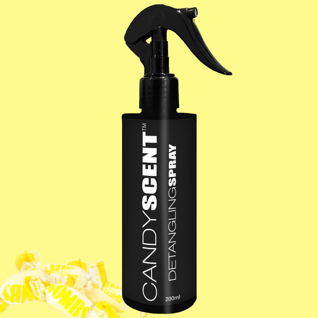 A black spray bottle labeled "CANDYSCENT™ Hair Detangling Spray, 200ml" is showcased against a vibrant yellow background. The bottle features a trigger spray nozzle and the formula is enriched with aloe vera for extra nourishment. In the bottom left corner, yellow candy wrappers are scattered, accentuating the overall theme.
